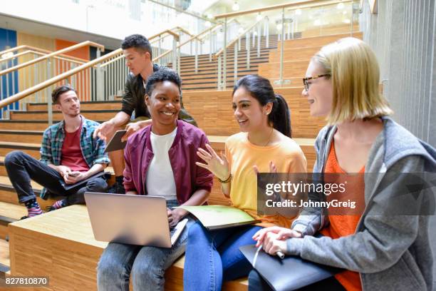 fröhliche weibliche college-freunde sitzen auf stufen mit laptop und ordner - indian college students stock-fotos und bilder