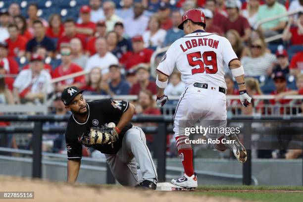 Jose Lobaton of the Washington Nationals is safe at first as Tomas Telis of the Miami Marlins bobbles the throw in the second inning at Nationals...