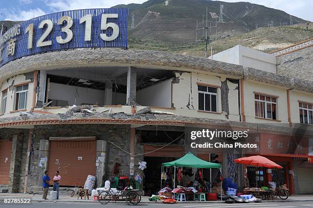 People carry on trade in front of a building destroyed during the earthquake on September 11, 2008 in Wenchuan County of Sichuan Province, China....