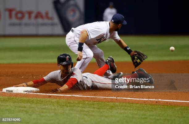 Mookie Betts of the Boston Red Sox reaches third base ahead of third baseman Trevor Plouffe of the Tampa Bay Rays as he advances from first base on...