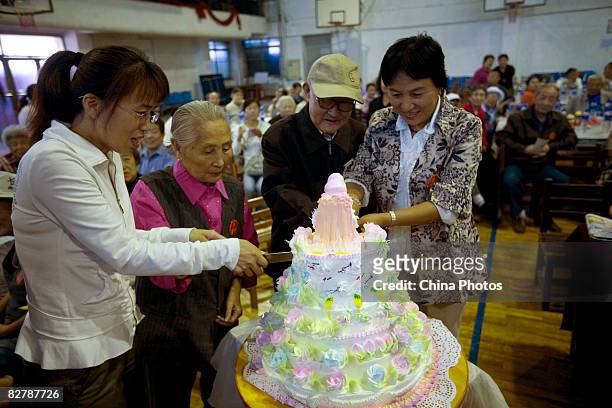 Married couple celebrating their golden wedding cut a cake with community staff members during a collective celebration of their golden wedding...