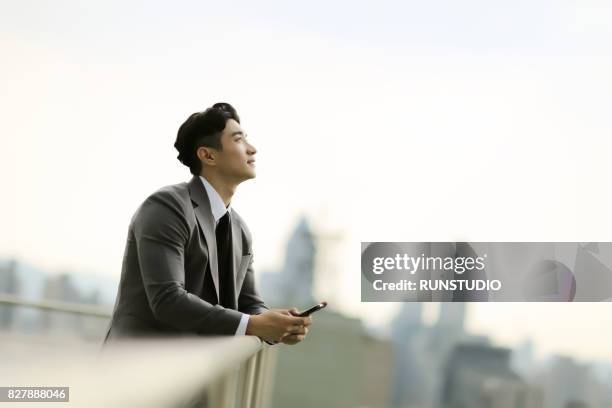 businessman standing on city rooftop - business man profile fotografías e imágenes de stock