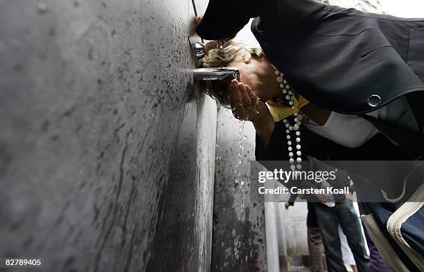 Woman drinks the holy water beside the Statue of Our Lady of Lourdes at the entrance to the Grotto of Massabielle on September 12, 2008 in Lourdes,...