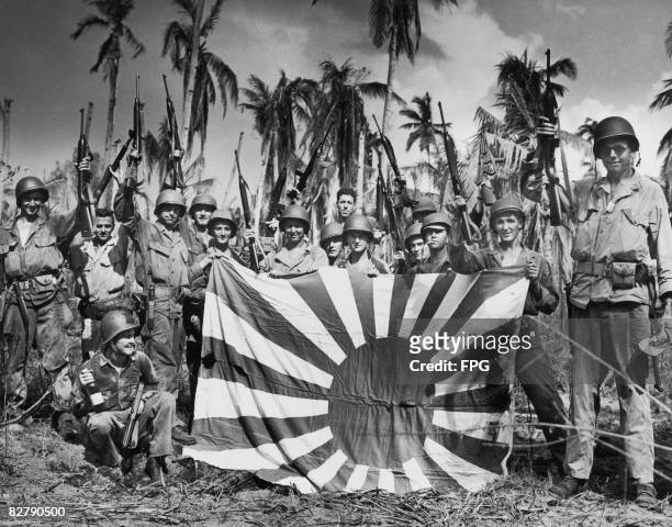 Coast Guardsmen and soldiers pose with a captured Japanese flag shortly after landing on Leyte Island on the first day of the Battle of Leyte in the...