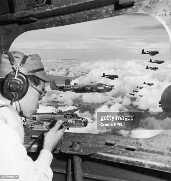 In the waist of a Marine bomber, Second Lieutenant Minoru Wada, a Japanese Army transport officer, who was captured on the Island of Mindanao, helps...