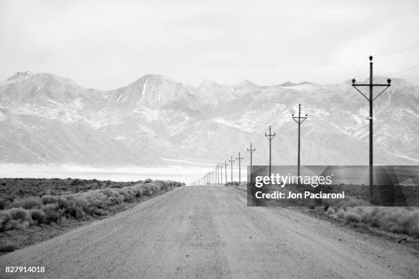 infrared long exposure of a lone road and power lines leading into the san juan mountain range. - contea di del norte foto e immagini stock