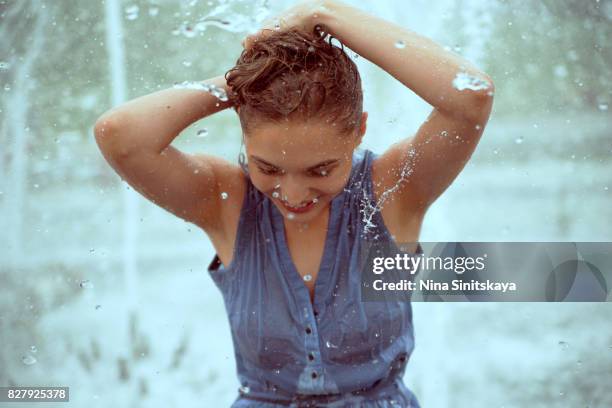 laughing cute girl in water splashes of fountain - wet hair stock pictures, royalty-free photos & images