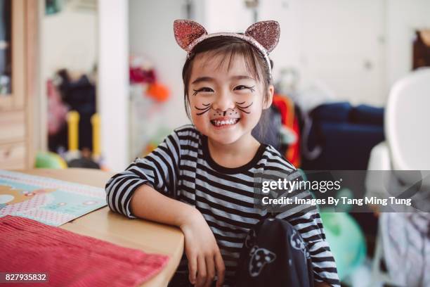 lovely little girl wearing a cat face painting smiling at camera joyfully at home. - face paint kids fotografías e imágenes de stock