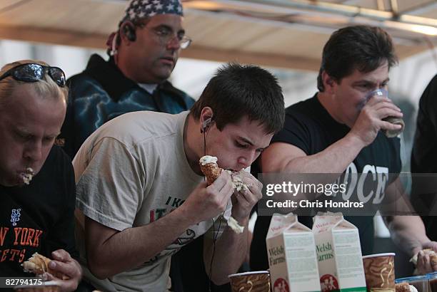 Competitive eater Brad Sciullo eats cannolis next to the competition including Allen Goldstein at the Annual Cannoli Eating Contest during the Feast...