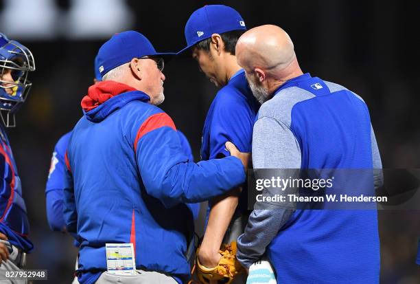 Koji Uehara of the Chicago Cubs with an apparent injury is looked at by manager Joe Maddon and trainer Ed Halbur during the bottom of the seventh...