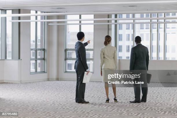 multi-ethnic business people viewing empty building - mann anzug von hinten stock-fotos und bilder