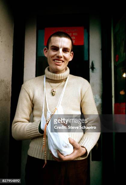 View of a devotee of the International Society for Krishna Consciousness , better known as Hare Krishna, as he stands outside a storefront temple,...
