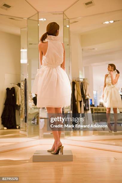 mixed race woman trying on dress in shop - kleidung anprobe stock-fotos und bilder