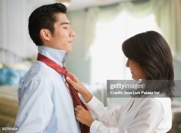 eurasian woman tying korean man's tie - eurasian female stock pictures, royalty-free photos & images