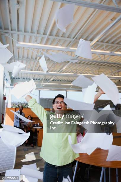 asian american businessman throwing papers in air - exhilaration stock pictures, royalty-free photos & images