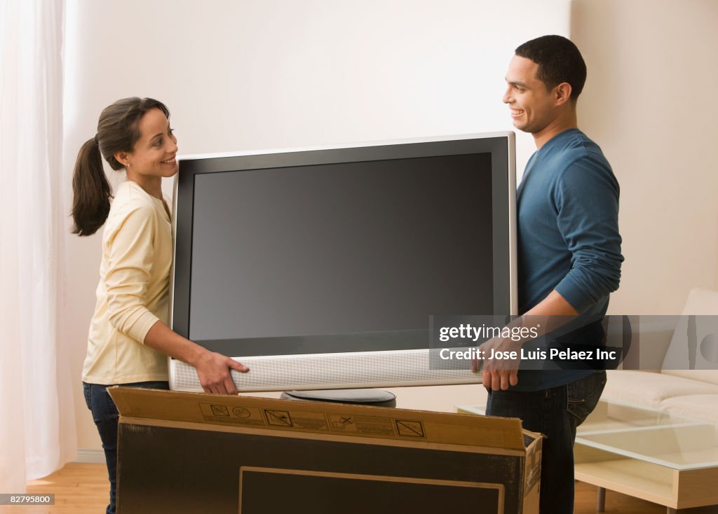 Hispanic couple carrying new television