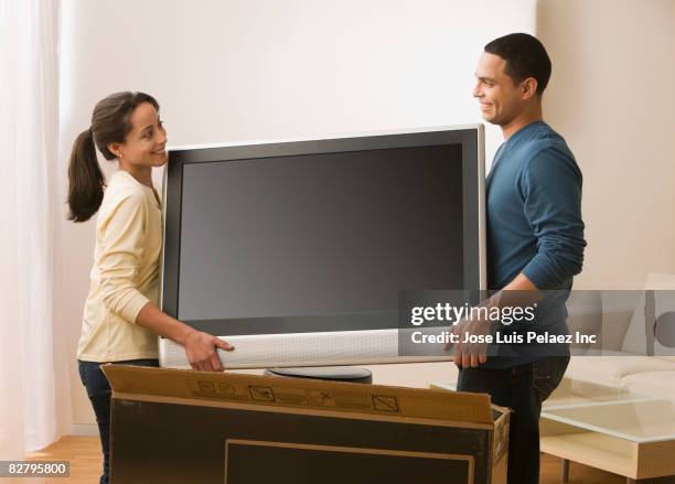 hispanic couple carrying new television - new boyfriend stock pictures, royalty-free photos & images