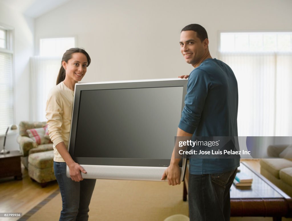 Hispanic couple carrying television