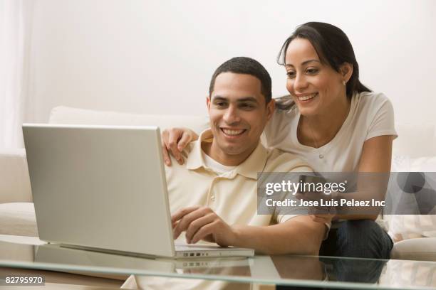 hispanic couple online shopping in living room - puerto rican people stock pictures, royalty-free photos & images