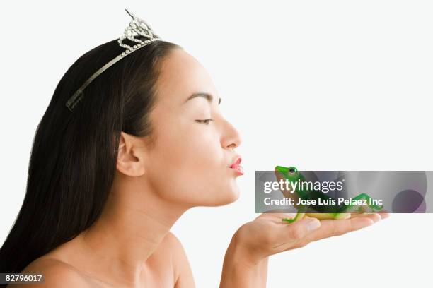 mixed race woman with tiara kissing toy frog - woman tiara stock pictures, royalty-free photos & images