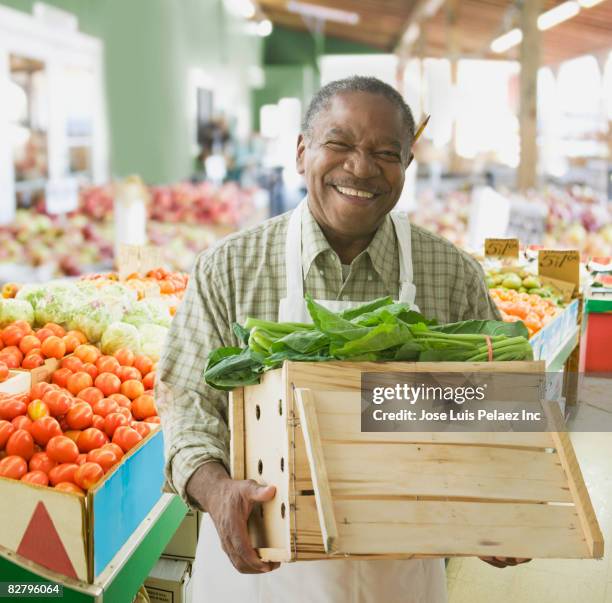 african grocer holding box of lettuce - groenteboer stockfoto's en -beelden