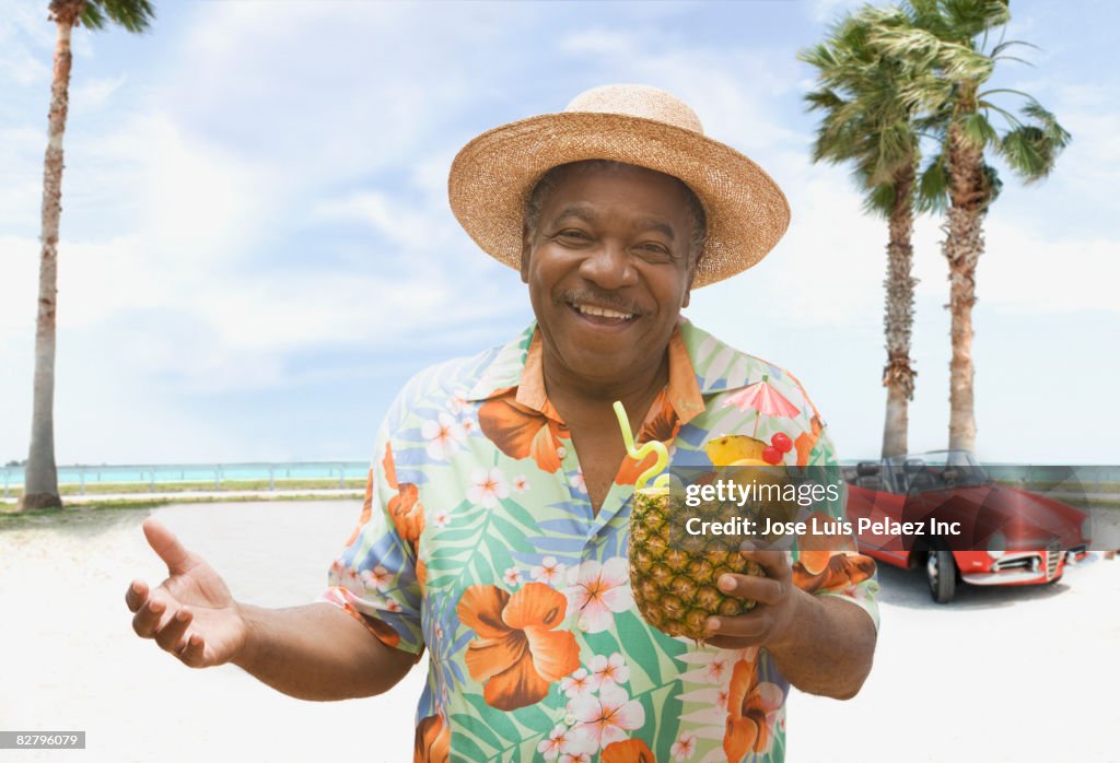 African man holding pineapple drink on tropical beach