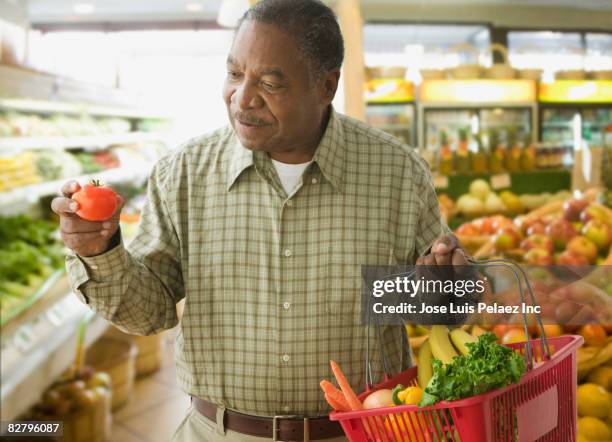 african man shopping for produce in grocery store - older black people shopping stock pictures, royalty-free photos & images