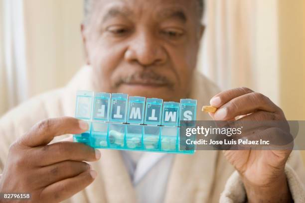 african man holding daily pill box with pills - auffüllen stock-fotos und bilder