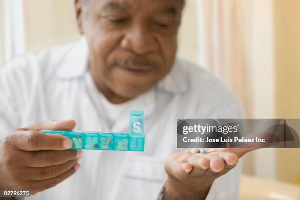african man holding daily pill box with pills - contenitore organizer per pillole foto e immagini stock