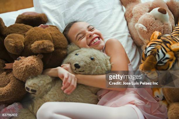 hispanic girl hugging teddy bear in bed - child teddy bear stock-fotos und bilder