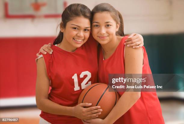 multi-ethnic girls hugging in basketball uniforms - cheek to cheek stock pictures, royalty-free photos & images