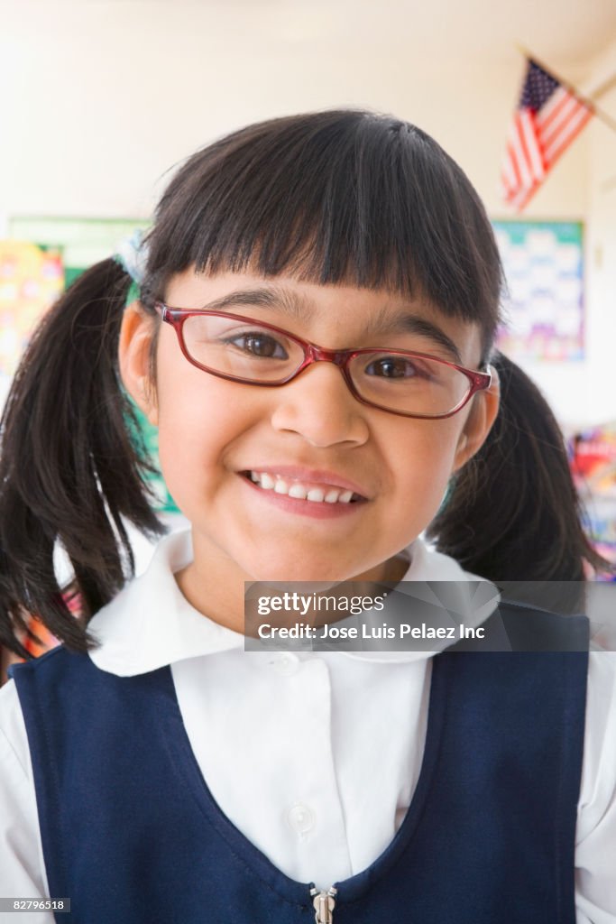 Close up of Hispanic girl wearing eyeglasses in classroom