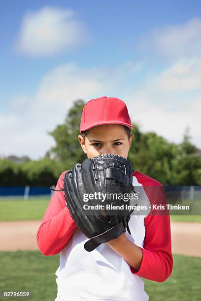 mixed race boy in baseball uniform holding glove and concentrating - baseball uniform stock pictures, royalty-free photos & images