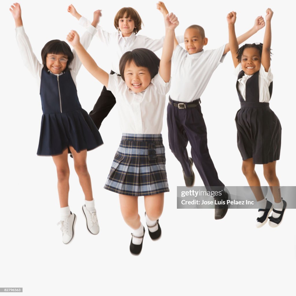 Multi-ethnic school children in uniforms jumping