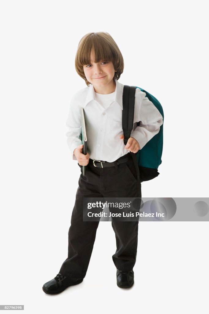 Mixed race school boy holding backpack and notebook