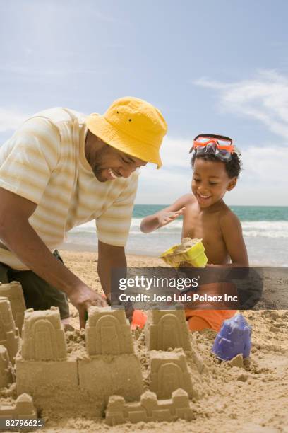 african father and son building sandcastle on beach - sand castle stock pictures, royalty-free photos & images