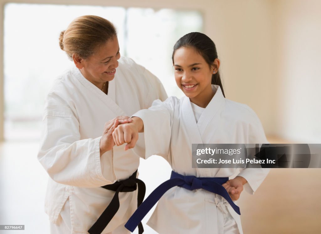 Hispanic woman teaching girl martial arts