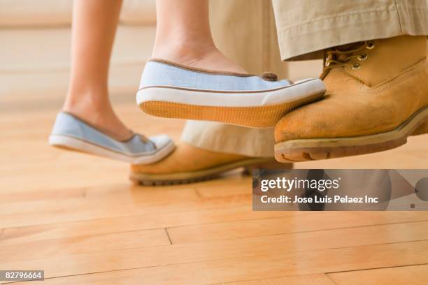 hispanic girl standing on father's toes - father daughter dance stock-fotos und bilder