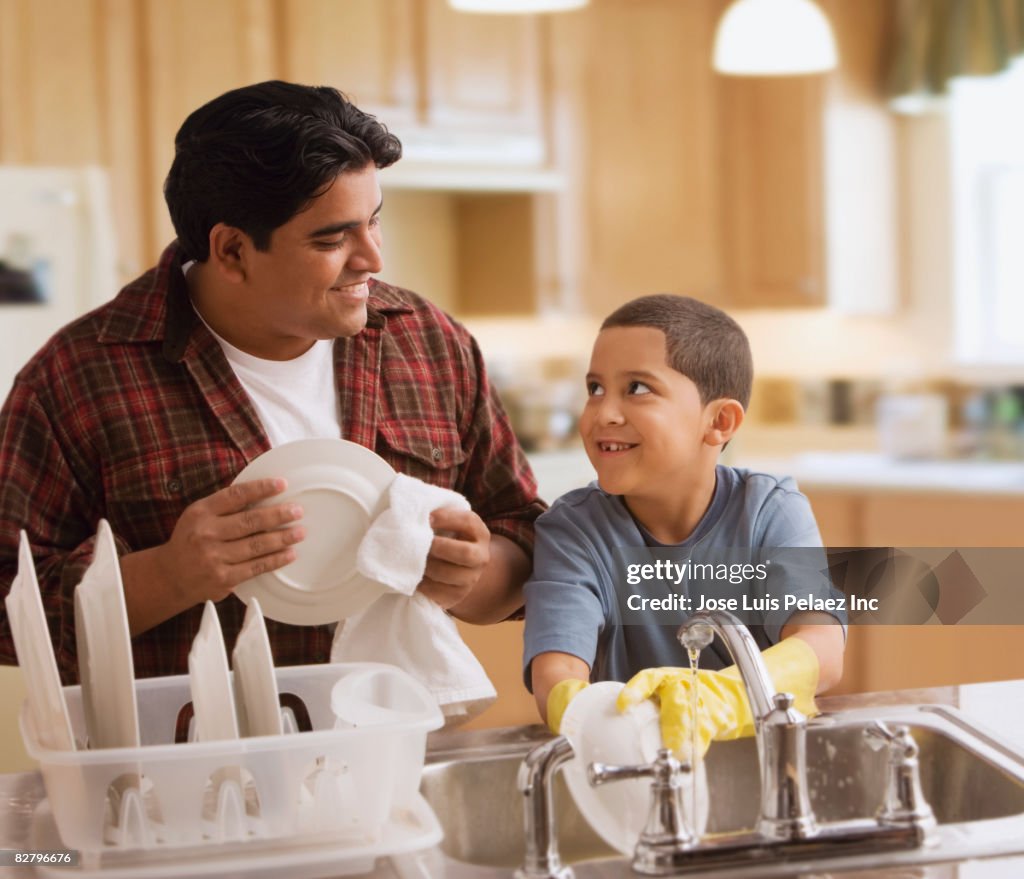 Hispanic father and son washing dishes