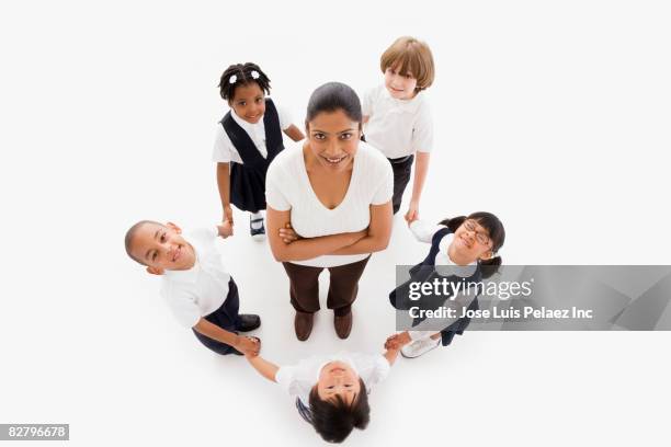 multi-ethnic school children forming circle around teacher - teacher standing stock pictures, royalty-free photos & images