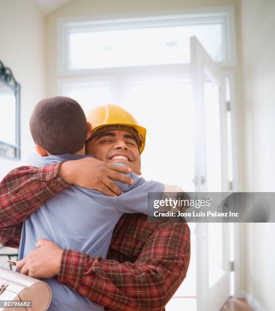 hispanic construction worker returning home and hugging son - homecoming imagens e fotografias de stock