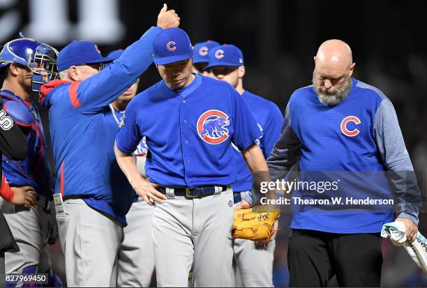 Manager Joe Maddon signals the bullpen to make a pitching change as pitcher Koji Uehara of the Chicago Cubs with an apparent injury is escorted off...