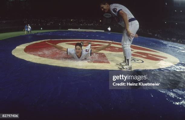 View of Chicago Cubs Greg Maddux and Les Lancaster playing "slip and slide" during rain delay vs Philadelphia Phillies. First night game in Wrigley...
