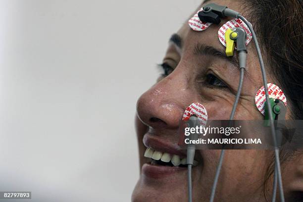 Brazilian armless Maria do Socorro Ferreira smiles as she types a message on the screen of a laptop through cables connected to her face using an...