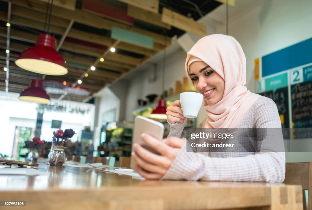Muslim woman at a cafe texting on her mobile phone