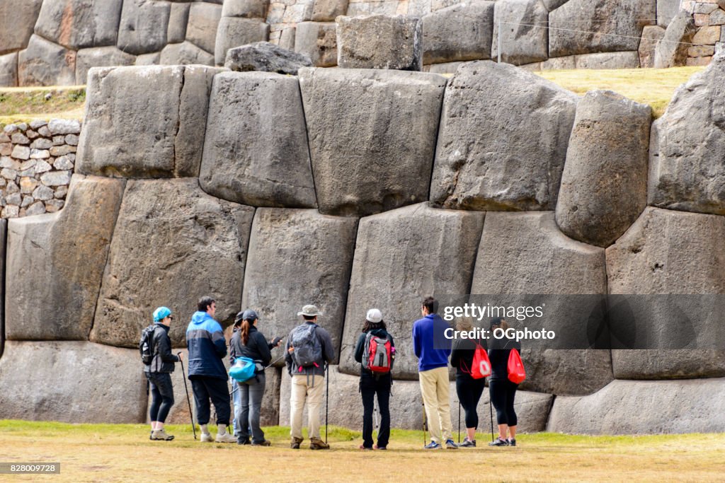 Turístico frente a gran pared de piedra en Saqsaywaman, Perú