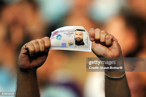 Manchester City fan holds a fake British Pound note with the face of Dr Sulaiman Al Fahim during the Barclays Premier League match between Manchester...