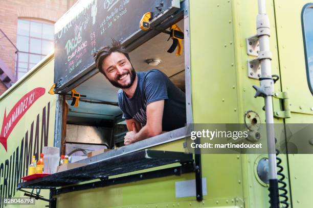 uomo sorridente ai clienti nel camion di cibo nelle strade della città. - furgone ambulante foto e immagini stock