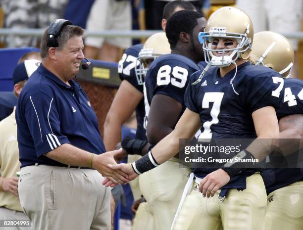 Jimmy Clausen of the Notre Dame Fighting Irish is congratulated by head coach Charlie Weis after a first quarter touchdown against the Michigan...