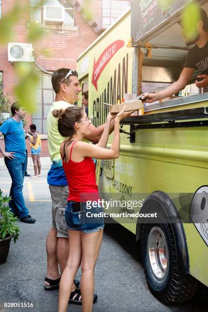 father and adult daughter taking out lunch from food truck in city street. - montreal street stock pictures, royalty-free photos & images